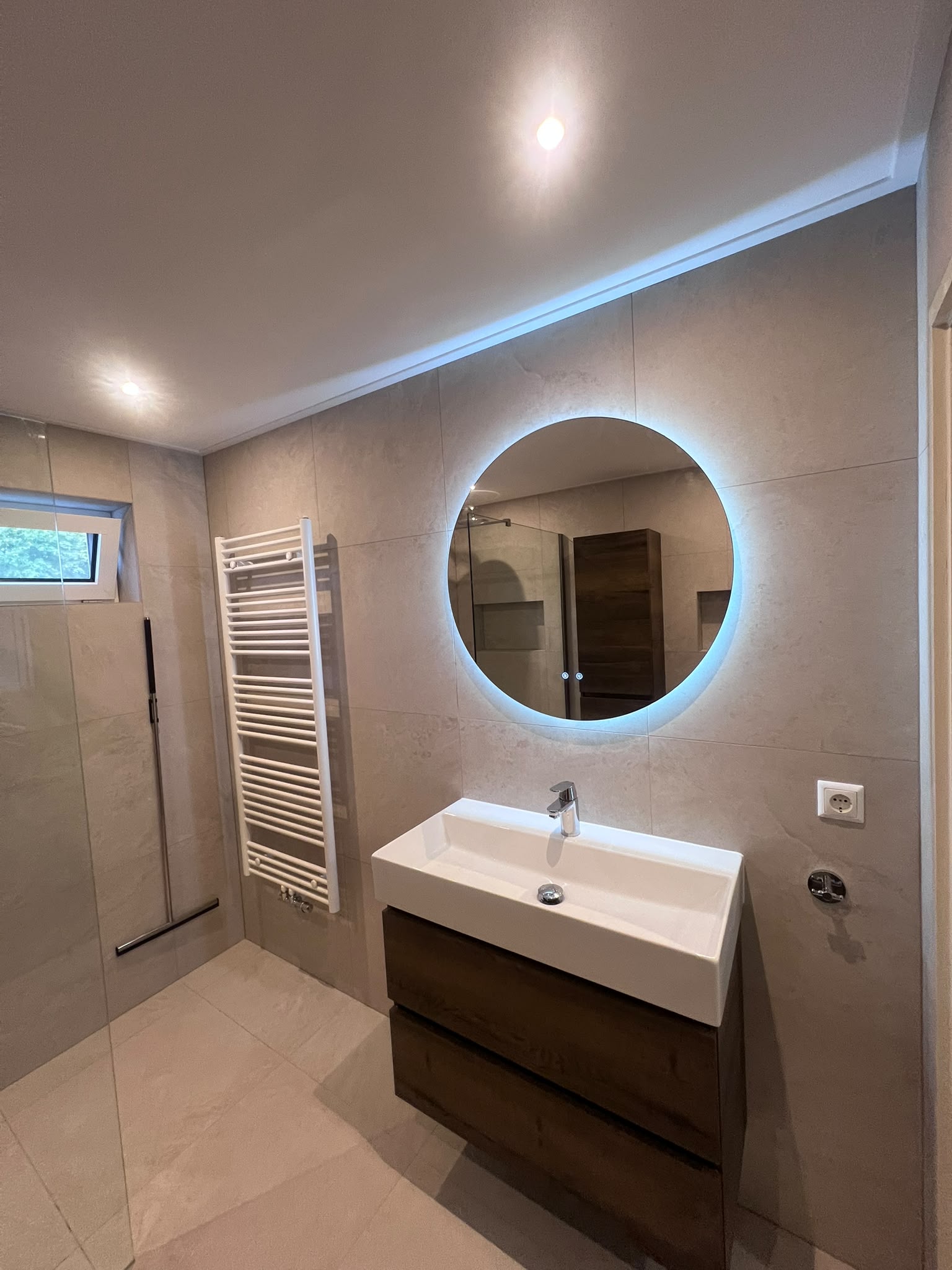 Zwevend wastafelmeubel in houtlook met ronde verlichte spiegel en witte handdoekradiator