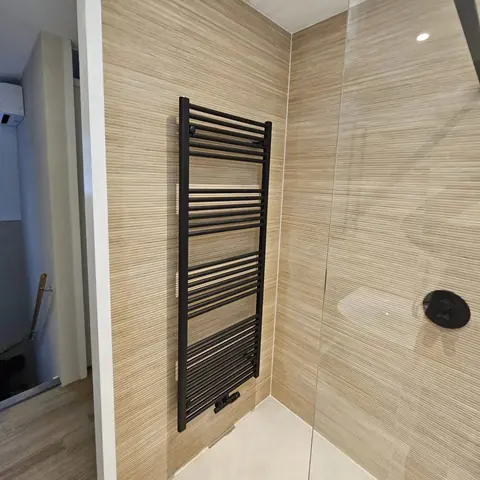 Zwarte designradiator tegen ribbelwand — badkamerrenovatie in Nijmegen