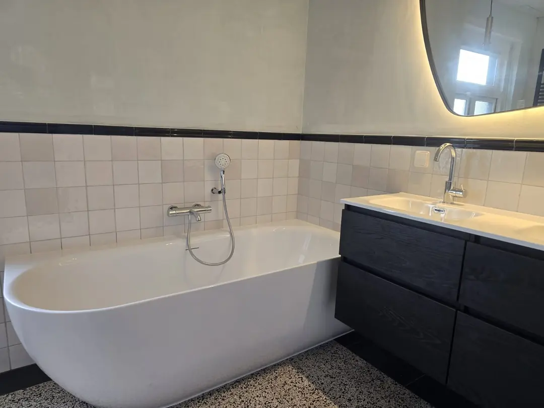 Ligbad met retro tegelwerk en zwart meubel — badkamerrenovatie in Nijmegen