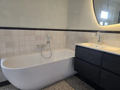 Ligbad met retro tegelwerk en zwart meubel — badkamerrenovatie in Nijmegen
