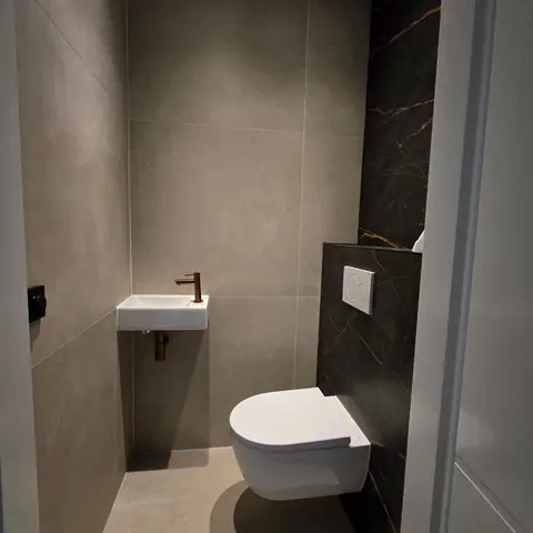 Toilet met marmerwand en koperen kraan — toiletrenovatie in Nijmegen