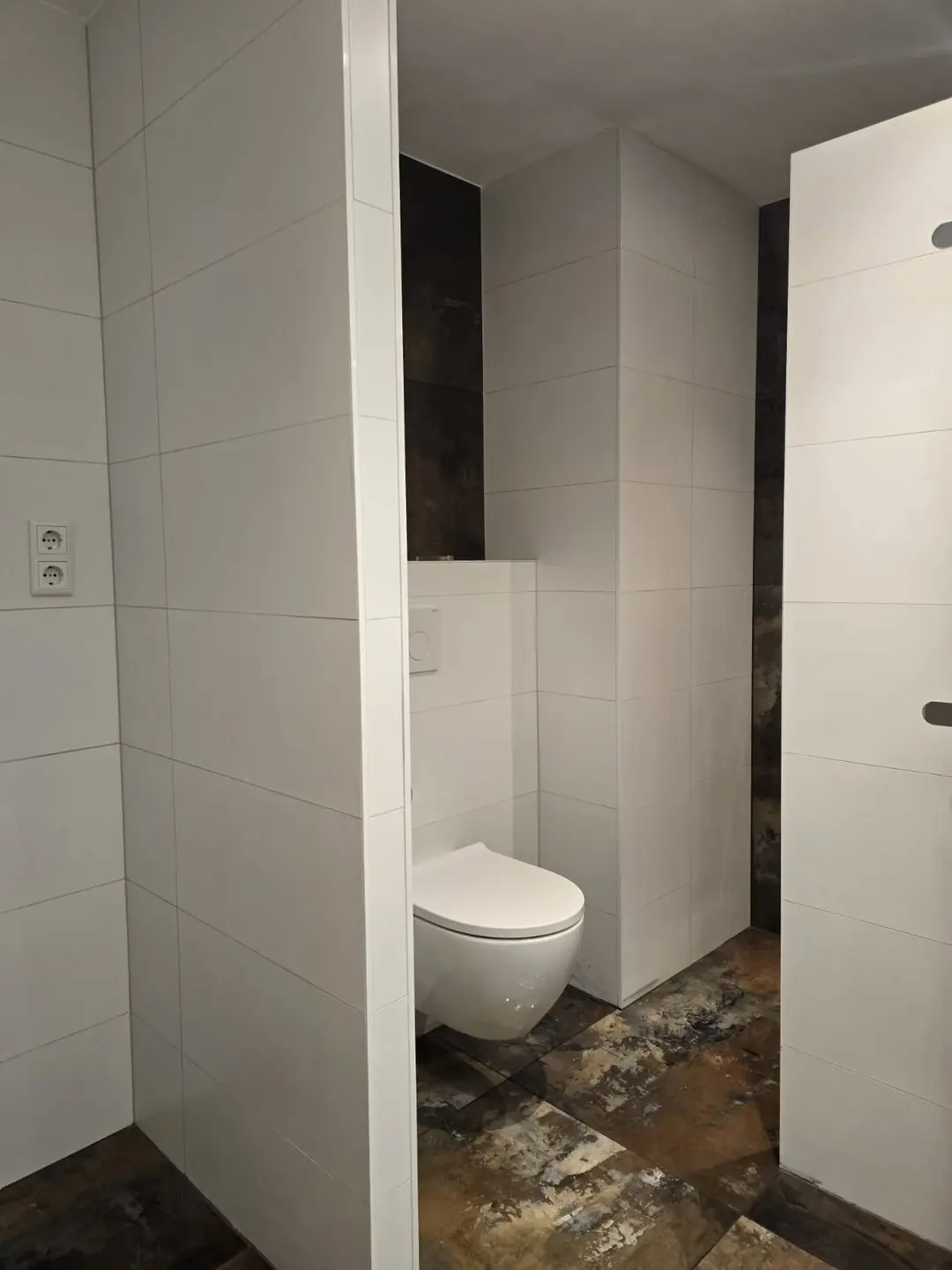 Toiletruimte met witte tegels en roestlook vloer — toiletrenovatie in Nijmegen