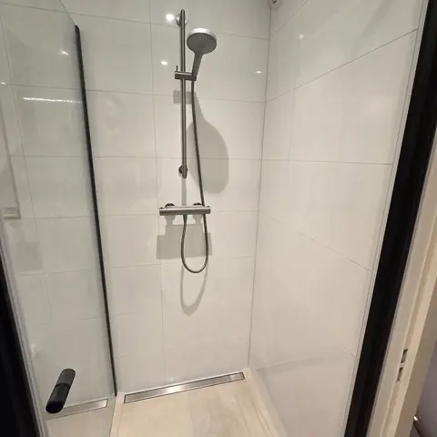 Strakke witte douche met RVS goot — badkamerrenovatie in Nijmegen